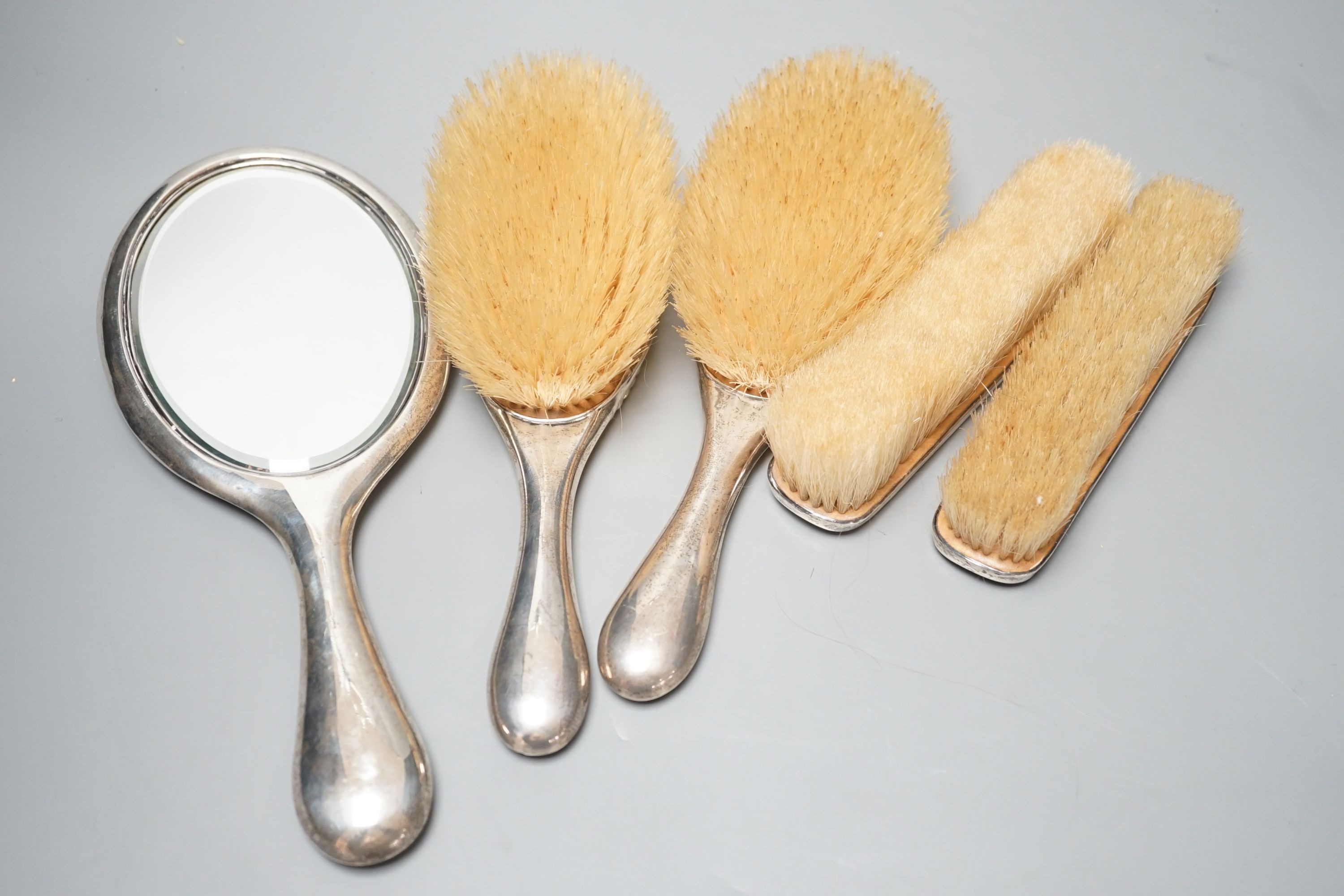 An early 20th century matched five piece silver mounted mirror and brush set.